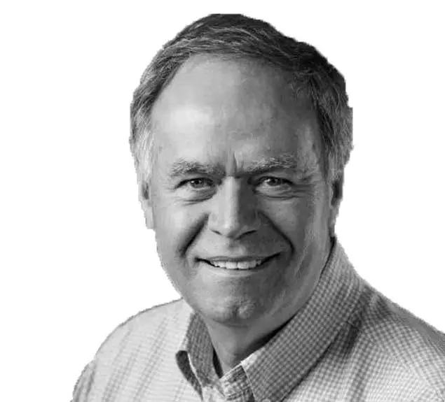 Black and white portrait of a smiling man with gray hair wearing a checkered shirt.