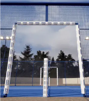 A blue soccer goal with a net, positioned on a sports field with a clear sky.