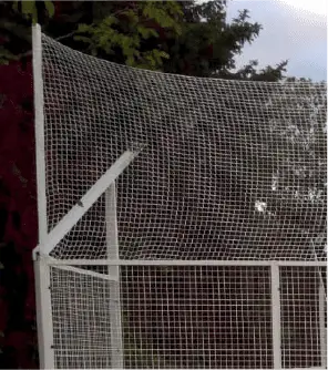 White sports netting structure with a sloped top for ball containment.