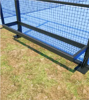 Metal bench with a grid design, installed at a sports facility near a playing surface.