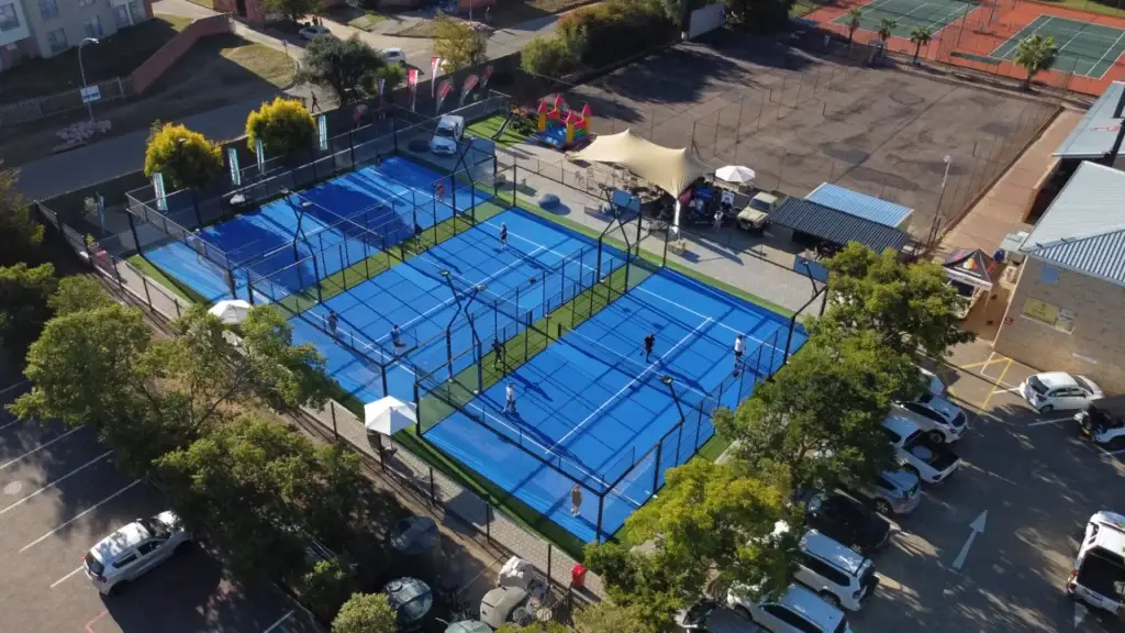 Aerial view of multiple blue tennis courts with players engaged in a match.