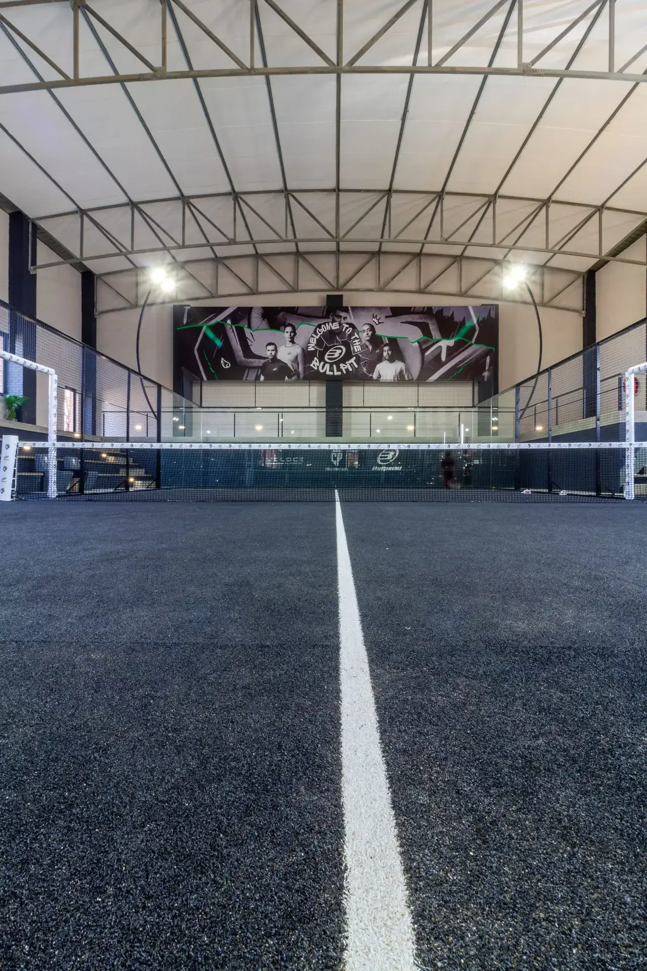 Indoor padel court with a distinctive surface and mural on the wall