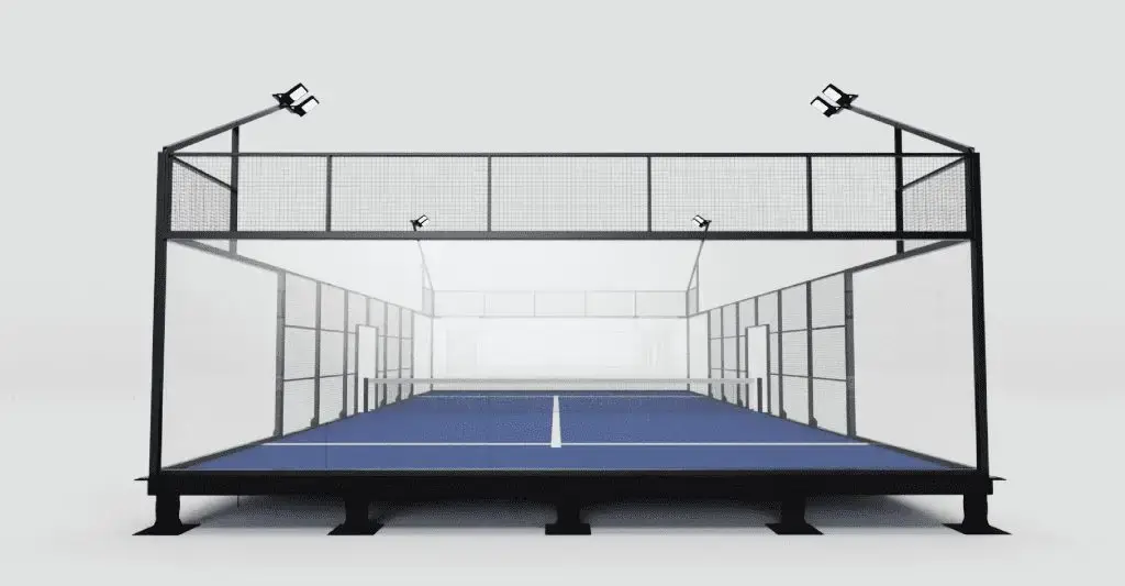 A padel court featuring a blue playing surface and glass walls, illuminated by overhead lights